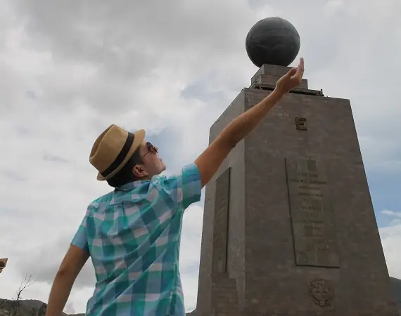 junger Mann vor dem Mite der Welt Denkmal bei Quito