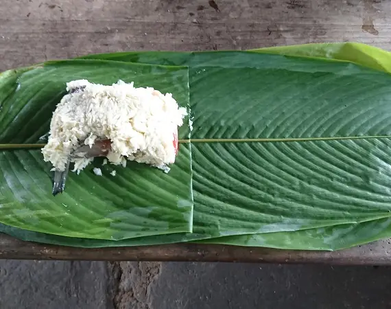 Fisch und zerkleinerte Palmherzen in einem Blatt
