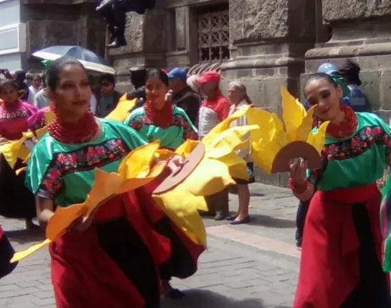 Eine Parade mit traditionell gekleideten Tänzerinnen in Quito