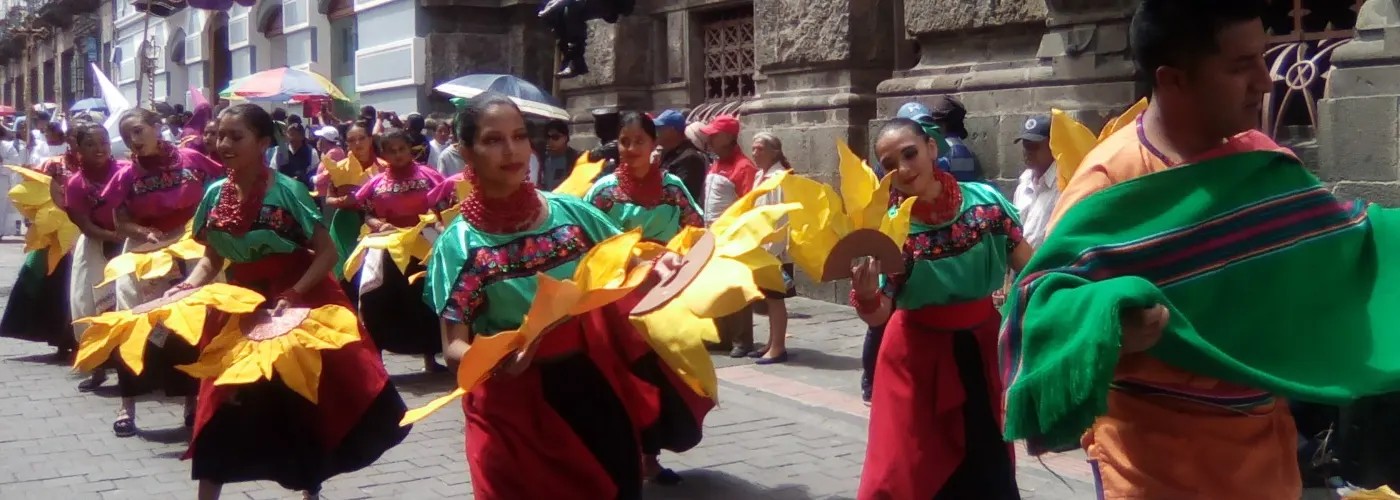 Eine Parade mit traditionell gekleideten Tänzerinnen in Quito